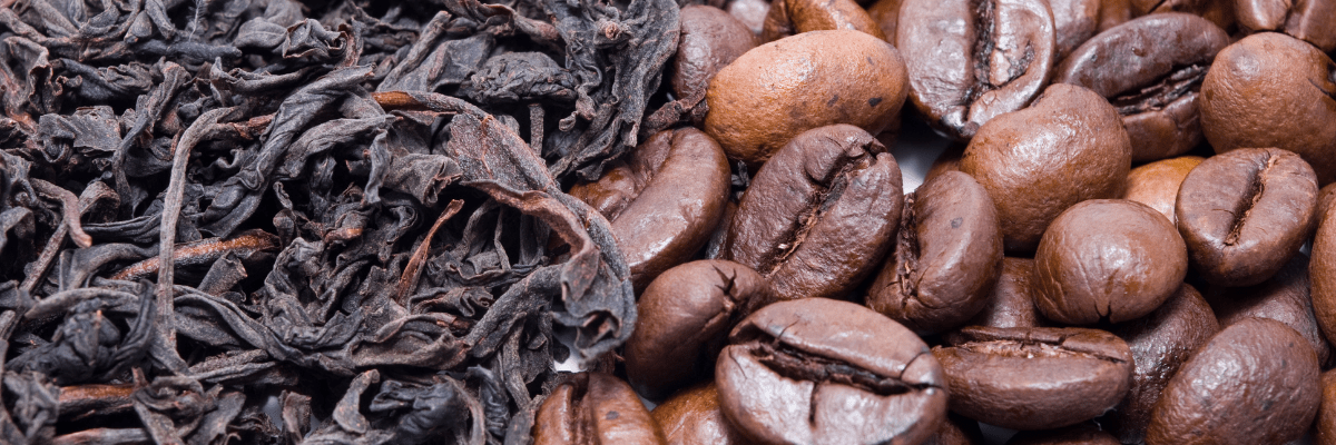 Close-up of loose black tea leaves beside roasted coffee beans.