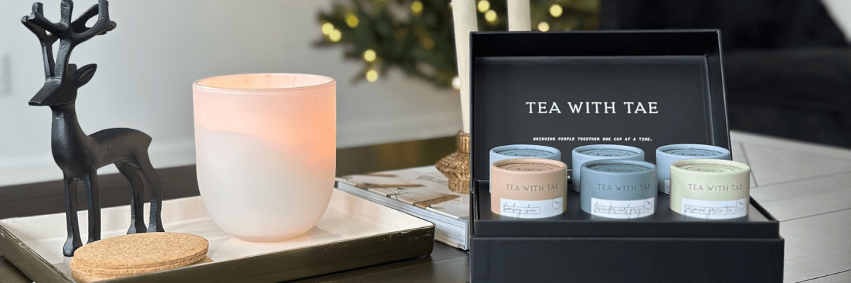 Tea Bento Box displayed open with assorted tea tubes beside a lit candle and decorative reindeer figure on a tabletop.