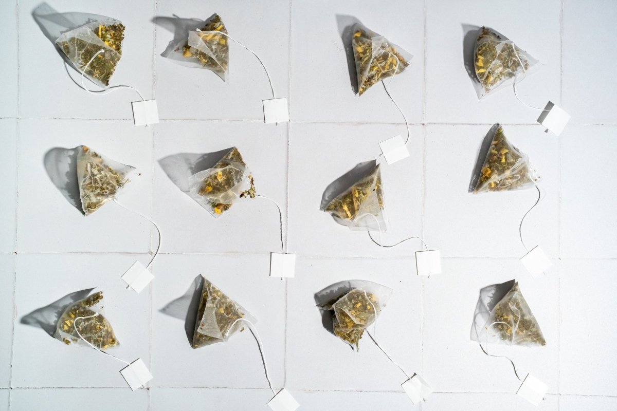 Several tea pyramid bags under bright light in a white background.