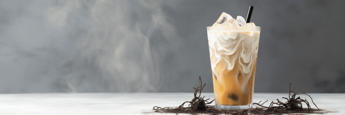 Tall glass of iced Coconut London Fog with creamy swirling layers, ice cubes, and a straw on a clean surface.