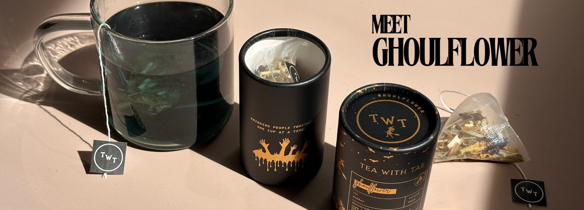 Ghoulflower tea packaging with black containers and a glass of tea on a beige surface.